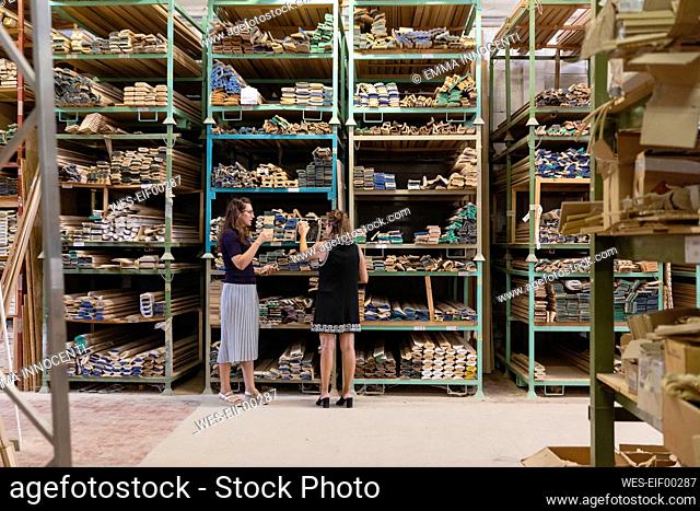Woman choosing wood while standing at warehouse of factory