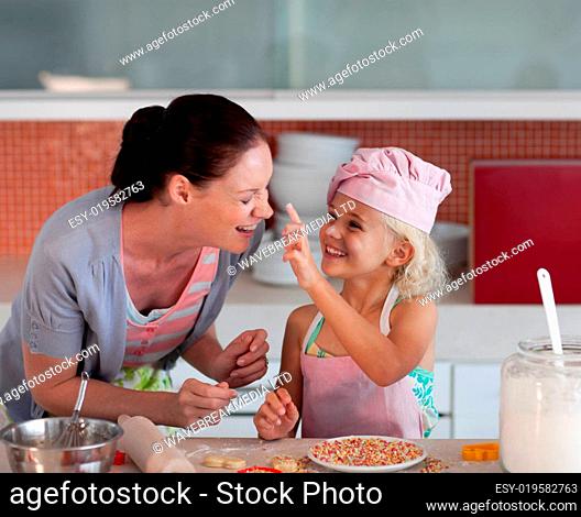 Smiling mother and her daughter baking in a kitchen