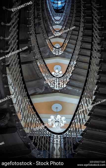 Sophisticated stairways with chandeliers on every floor, viewed from down to, as a pattern of geometric oval figures, in a hotel in Genoa, Italy