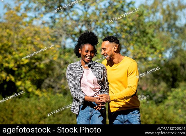 Smiling young couple having fun while walking in public park