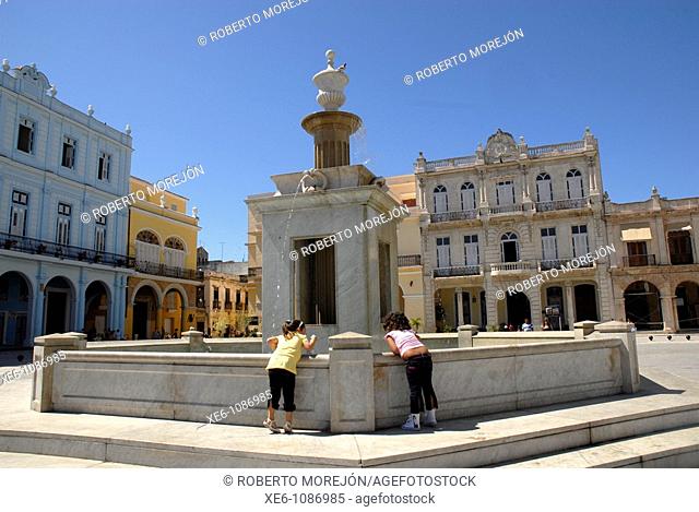 Carrara marble fountain, with an octagonal cup, located La Plaza Vieja in Havana, Cuba with the surrounding buildings from the colonial period