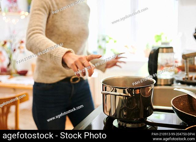 PRODUCTION - 29 April 2021, Berlin: A mother jumps to the hot pot in the kitchen. Photo: Annette Riedl/dpa. - Berlin/Berlin/Germany