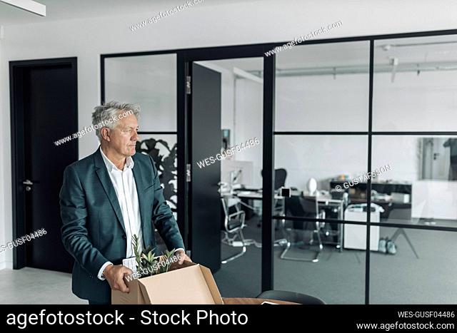 Businessman holding box while standing at office