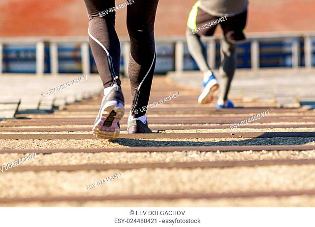 fitness, sport, exercising and lifestyle concept - close up of couple running downstairs on stadium