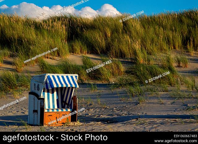 Strandkorb im Abendlicht am Strand auf der ostfriesischen Nordseeinsel Juist in Deutschland, Europa. Beach chair in evening light on the beach of the north sea...