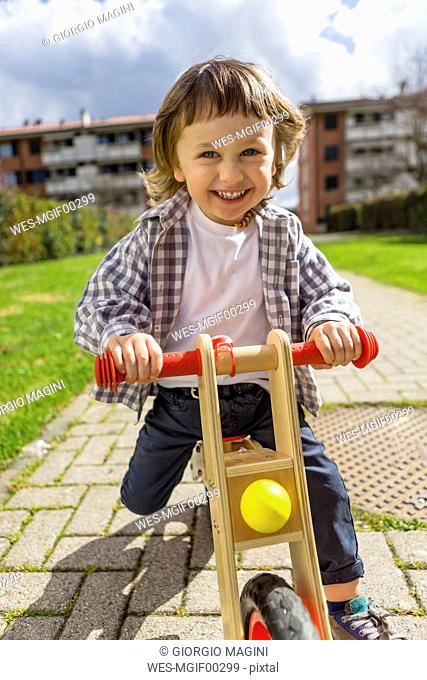 Portrait of happy toddler boy with balance bicycle on a path