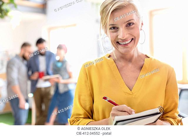 Portrait smiling female design professional taking notes in notebook in office