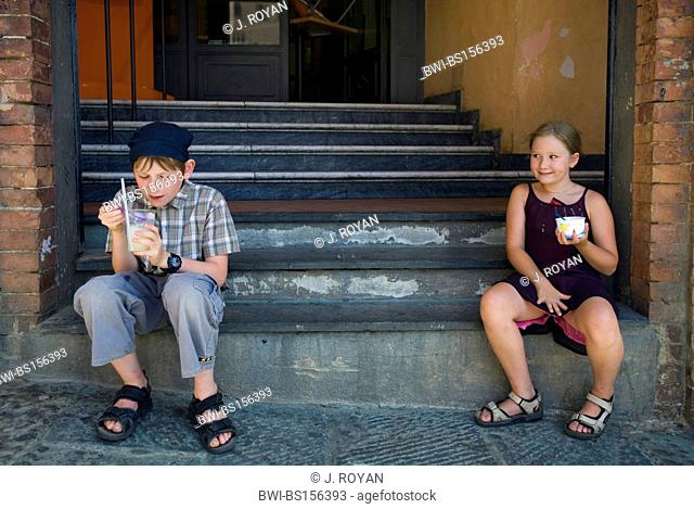 A boy and a girl eating Ice Cream in the front steps of a building, Italy, Siena