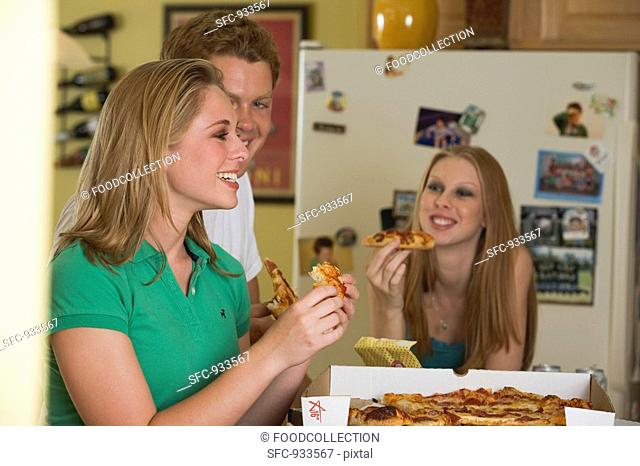Three young people eating pizza