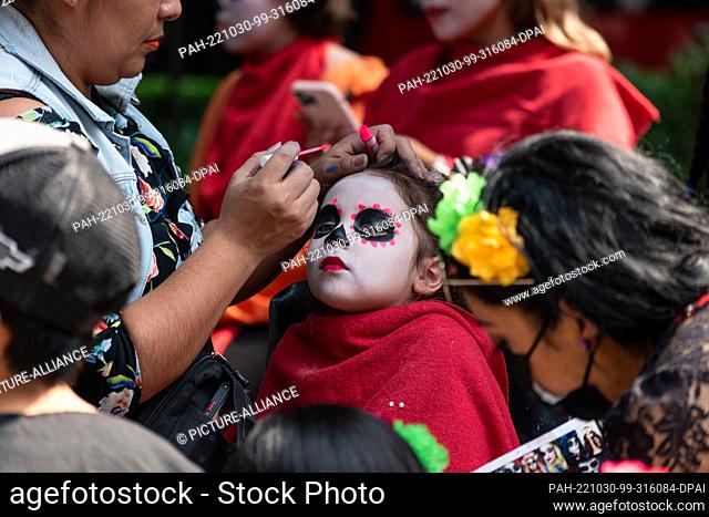 dpatop - 29 October 2022, Mexico, Mexiko-Stadt: A girl made up as Catrina, as part of the traditional parade. Hours before the start of the event