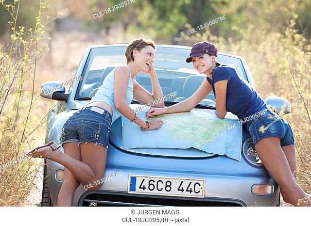 Two women reading a map on a car bonnet