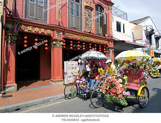 Tourist rickshaws pass well known chicken rice ball Famosa Restaurant Malacca Malysia