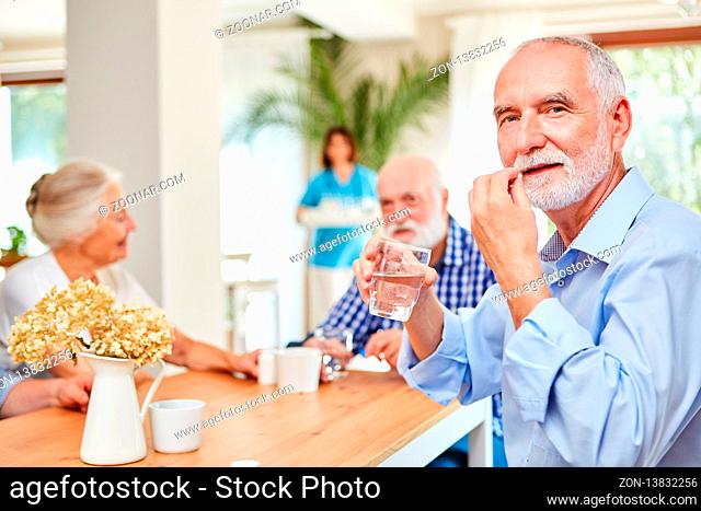 Senior Mann nimmt Tablette mit einem Schluck Wasser ein im Seniorenheim