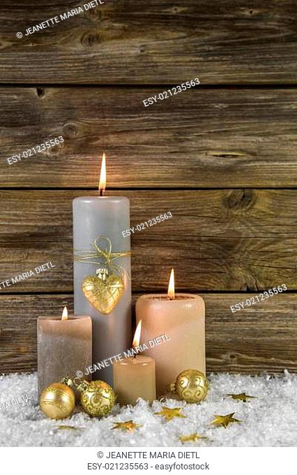 Traditional christmas decoration with four beige burning advent candles on wooden background