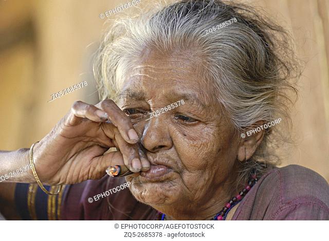Closeup of a Warli Tribal Old Woman smoking bidi, an Indian handmade cigarette made of tobacco or beedi leaves