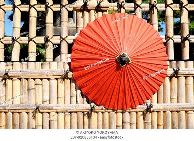 Traditional Japanese red umbrella with bamboo fence