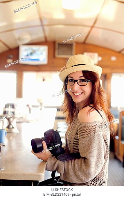 Caucasian woman holding camera in restaurant