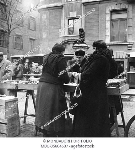 Women shopping at the street market in piazza delle Erbe. Trento, December 1954
