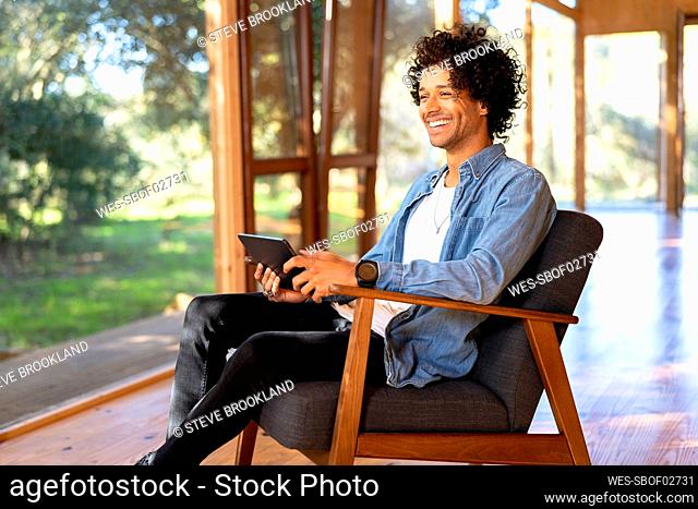 Smiling man using digital tablet while sitting at front yard