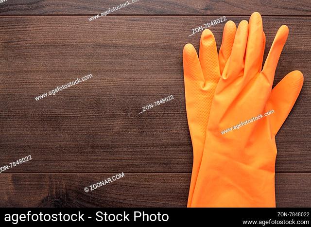 orange rubber cleaning gloves on wooden background
