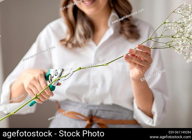 woman cutting flower stem with pruning shears