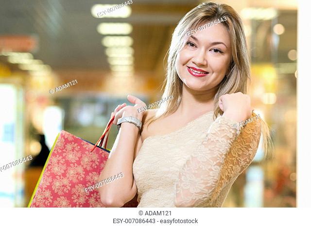 portrait of a beautiful woman in a shopping center, holding shopping bags and smiling