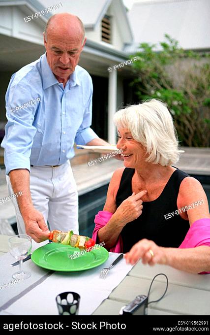 Senior man serving a variety of fish to a smiling woman
