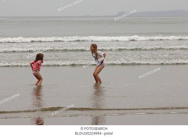 Two girls playing on ocean beach, Wickaninnish Beach, Vancouver Island, Canada