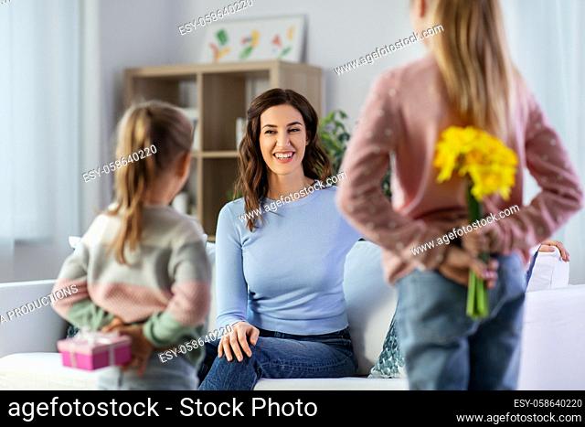 daughters giving flowers and gift to happy mother