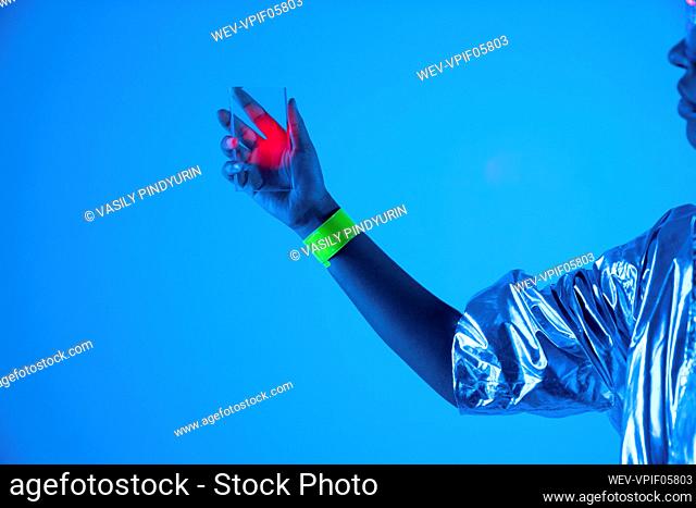 Young woman holding futuristic transparent smart phone against blue background