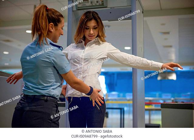 Security guard checking female passenger in airport security