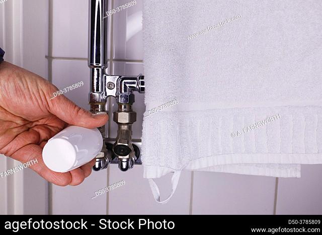 A hand checks the temperature of a hot towel rack in the bathroom