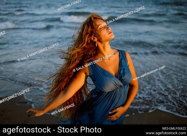 Beautiful woman dancing at beach during sunset