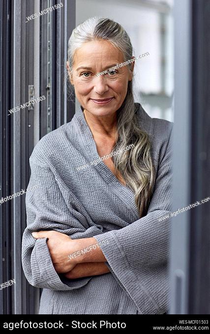 Confident mature woman with arms crossed standing in bathroom