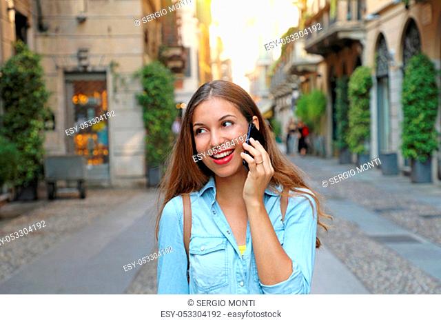 Happy young woman talking on mobile phone at city street lifestyle portrait. Close up portrait of a cheerful young woman making a phone call outdoors in Brera
