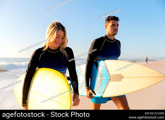 Caucasian couple holding surfboards at the beach