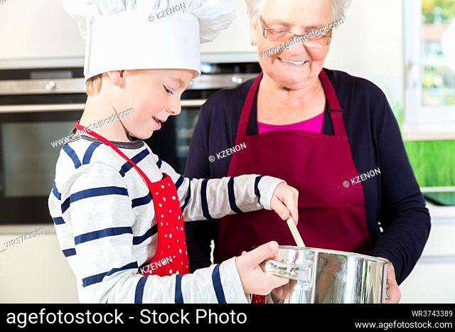 Granny and little boy preparing together food in kitchen