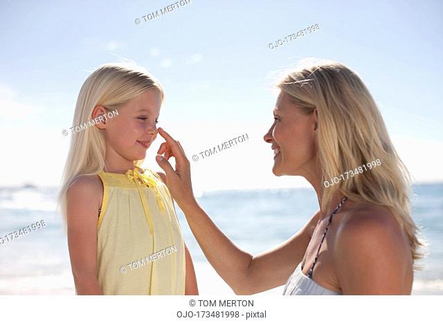 Mother applying sunscreen to daughter’s nose
