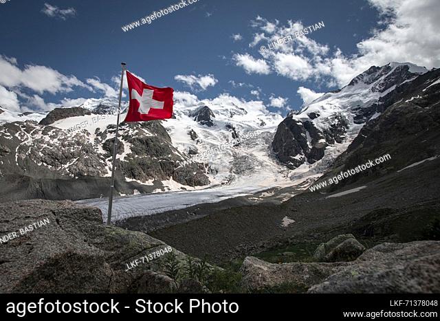 Glacier tongue of the Morteratsch Glacier in the Engadin in the Swiss Alps in summer with Switzerland flag