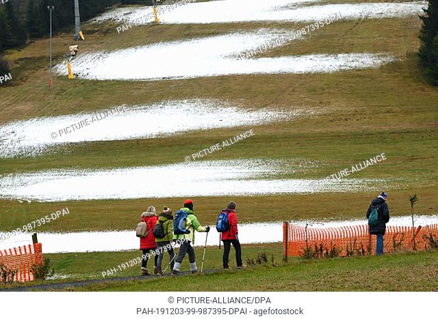 03 December 2019, Hessen, Willingen: A group of women walk up Ettelsberg past the first artificial snow fields on the ski slope