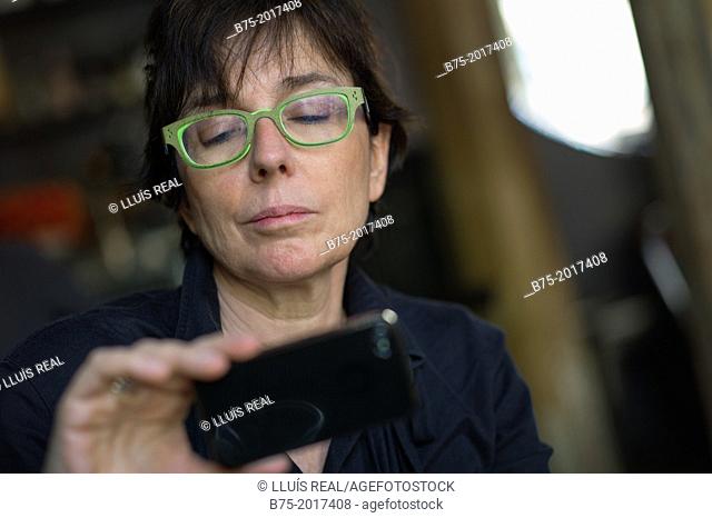 fifty years old lady looking at pictures on a mobile phone
