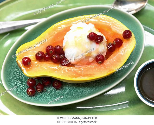 Papaya filled with ice cream and served with redcurrants