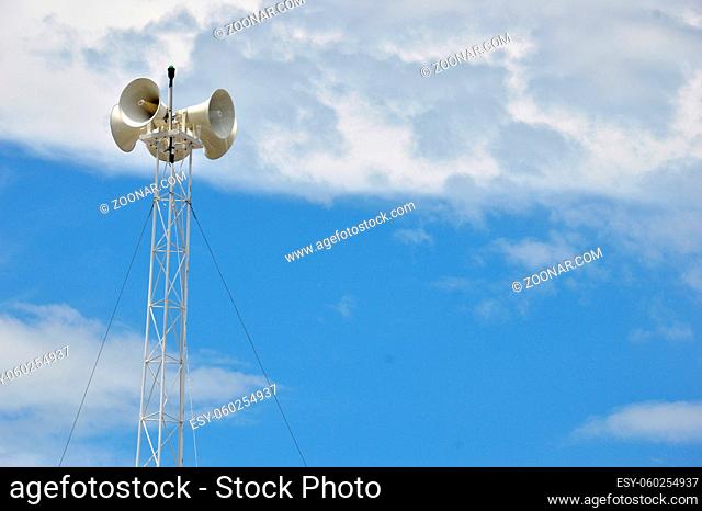 four metal loudspeakers against the the sky