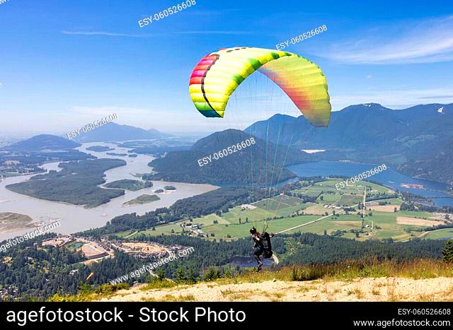 Adventurous Woman Running to Take Off the Mountain Top with a Paraglider to Fly. Harrison Mills near Chilliwack, British Columbia, Canada