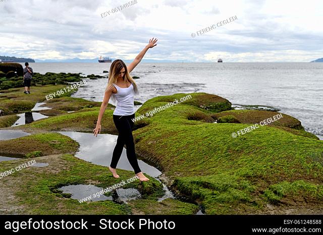 People exploring the intertidal zone of Vancouver, British Columbia. Those rocks are underwater at high tide, and out of water at low tide and revealing a...
