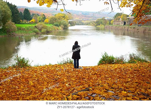 Autumn scene. Pensive woman at the river in Hannover Münden Germany