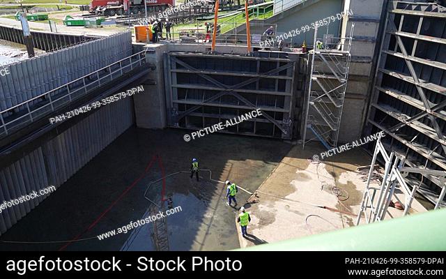 26 April 2021, Schleswig-Holstein, Husum: Workers prepare a gate of the barrage for craning. On Monday, the gates of the Husum barrage were lifted out of their...