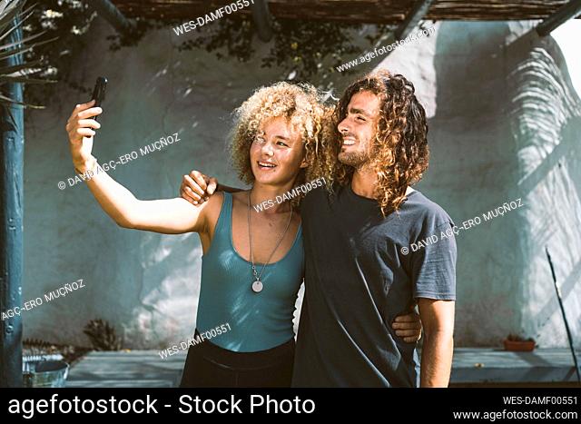 Friends taking selfie through mobile phone while standing outdoors