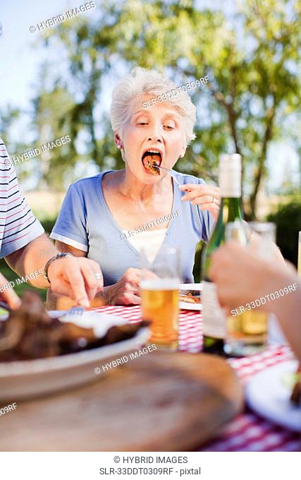 Older woman eating at picnic table