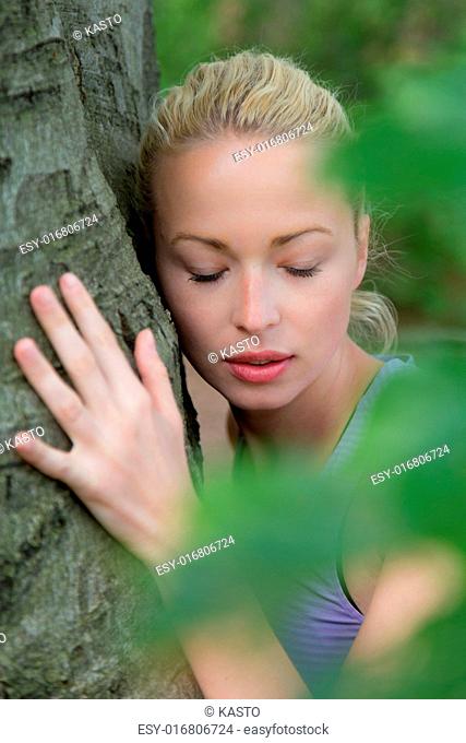 Relaxed young lady embracing a tree receiving life energy from the nature